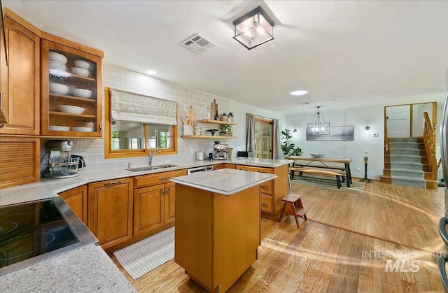 14 Cougar Ln, Boise, ID 83716 - kitchen featuring a sink, light wood finished floors, brown cabinetry, a peninsula, and glass insert cabinets