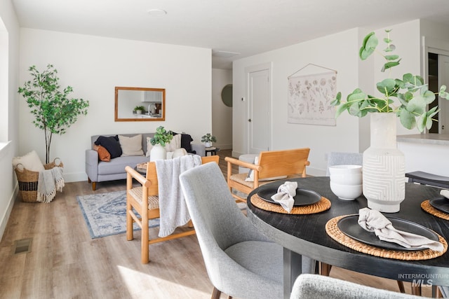 dining area featuring light wood-style floors, baseboards, and visible vents