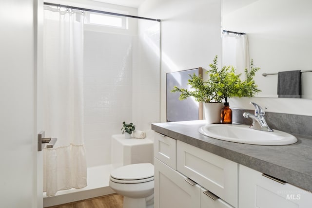 full bathroom featuring a stall shower, vanity, toilet, and wood finished floors