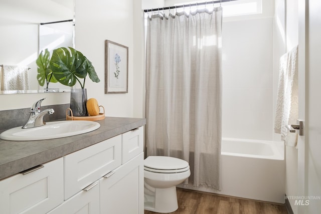 bathroom featuring toilet, wood finished floors, vanity, and shower / bathtub combination with curtain