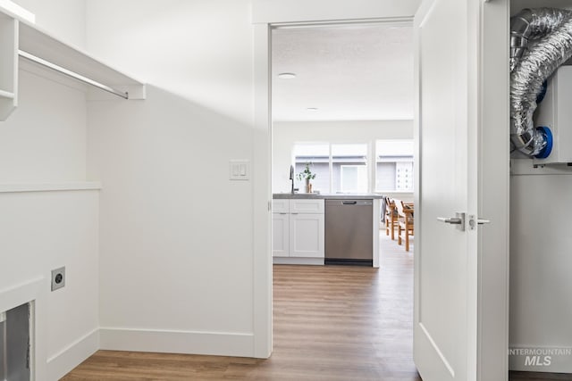 laundry area with light wood-type flooring, laundry area, electric dryer hookup, and baseboards