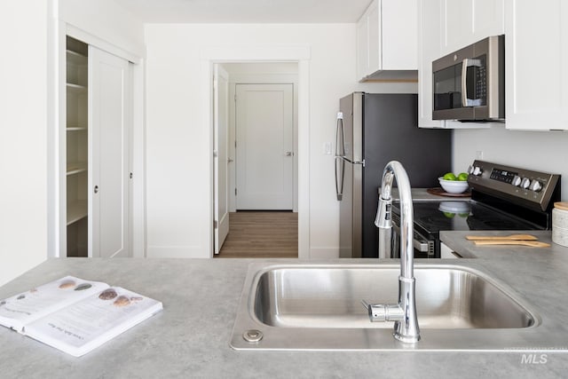 kitchen with stainless steel appliances, light countertops, and white cabinets