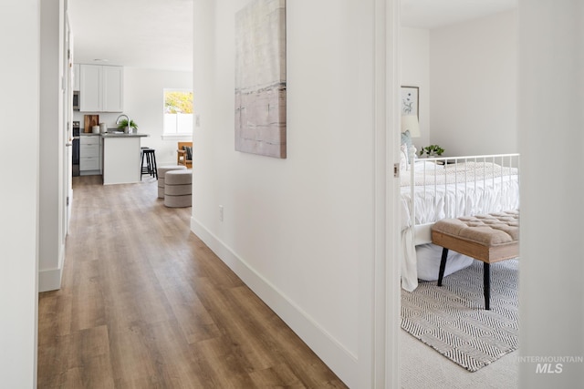 hallway with a sink, baseboards, and wood finished floors