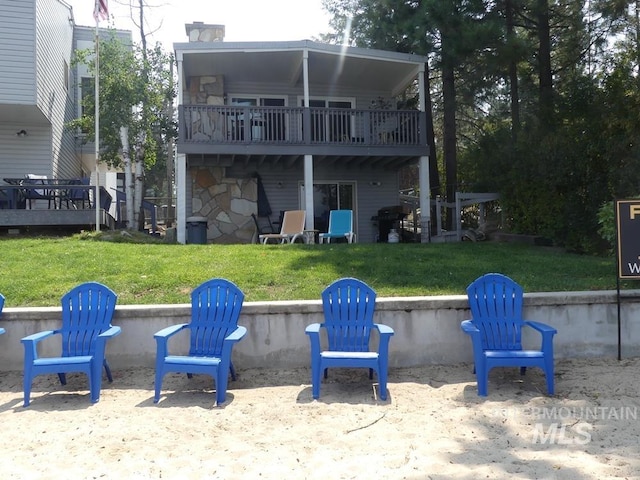 rear view of property with a balcony, a wooden deck, and a yard