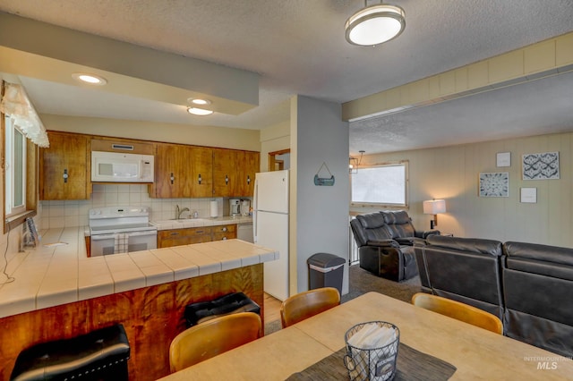 kitchen featuring white appliances, tile countertops, carpet, sink, and decorative backsplash