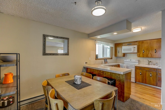 dining space featuring a textured ceiling, light wood-type flooring, sink, and baseboard heating