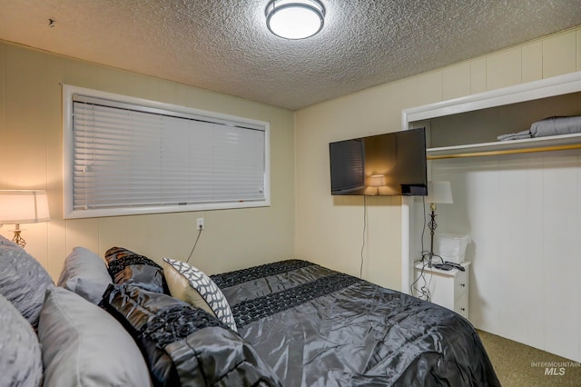 carpeted bedroom featuring a textured ceiling and a closet