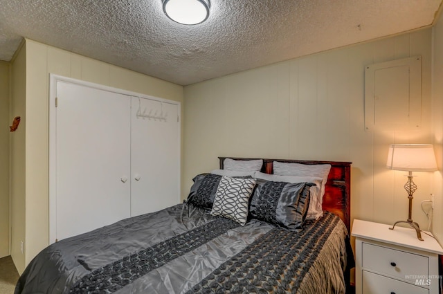 bedroom with a textured ceiling, carpet floors, and a closet