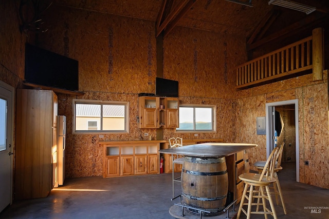1190 Devils Elbow Rd, Weiser, ID 83672 - kitchen featuring high vaulted ceiling, healthy amount of natural light, concrete floors, freestanding refrigerator, and brown cabinetry
