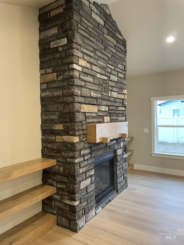 details with wood-type flooring and a stone fireplace