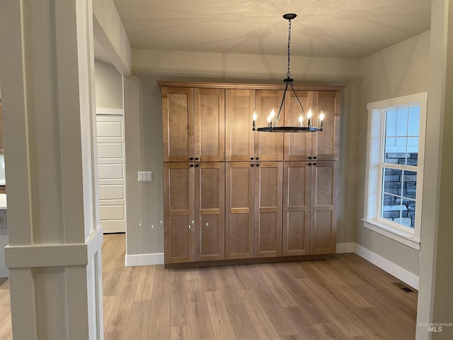 unfurnished dining area featuring a notable chandelier and light hardwood / wood-style floors