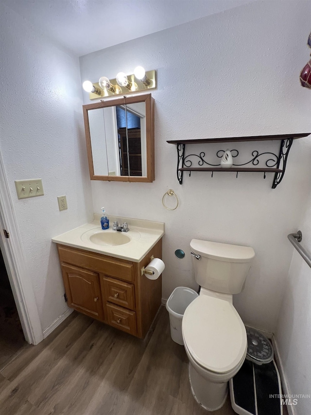 58438 Mansford Ave, Murphy Hot Springs, ID 83302 - half bathroom featuring baseboards, toilet, wood finished floors, and vanity
