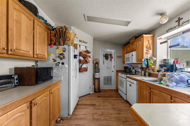 kitchen with vaulted ceiling, white appliances, a textured ceiling, and light wood-type flooring