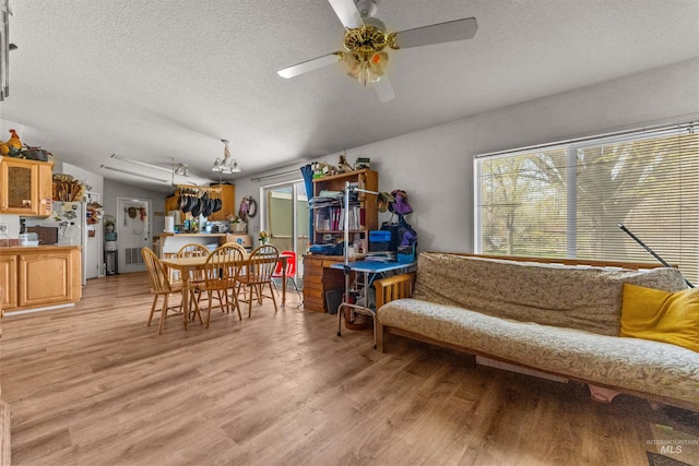 living area featuring ceiling fan, light wood-type flooring, and a textured ceiling