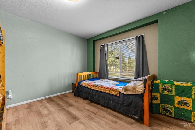 bedroom with light hardwood / wood-style flooring and a textured ceiling