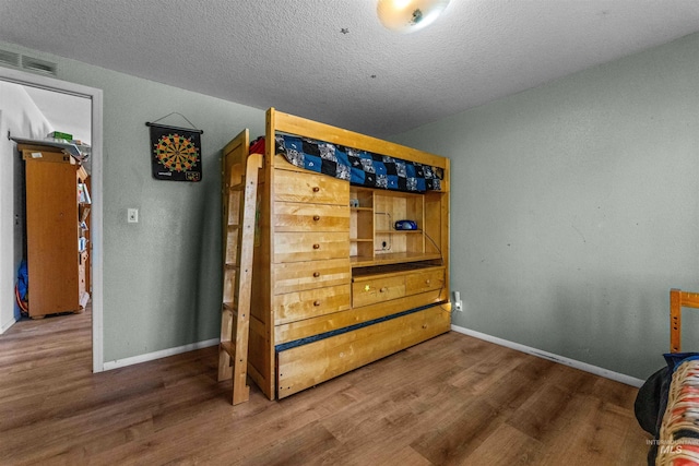 bedroom with a textured ceiling and hardwood / wood-style flooring