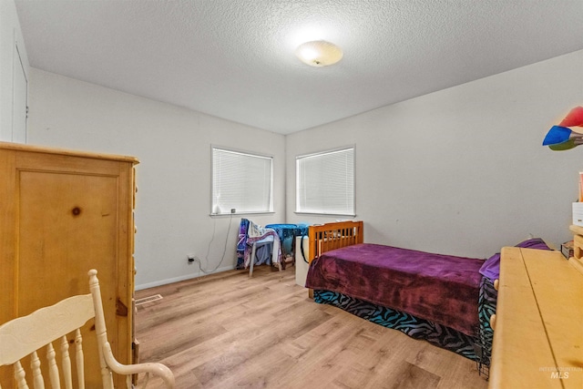 bedroom featuring light hardwood / wood-style flooring and a textured ceiling