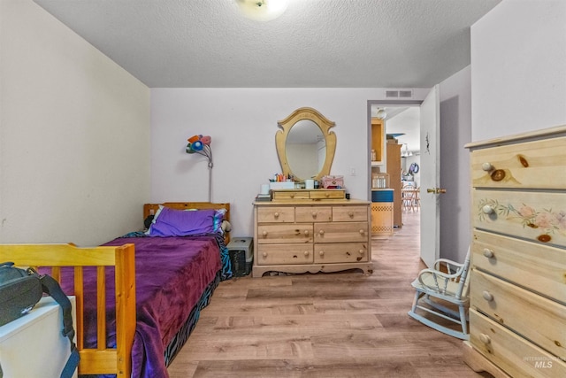 bedroom with light wood-type flooring and a textured ceiling
