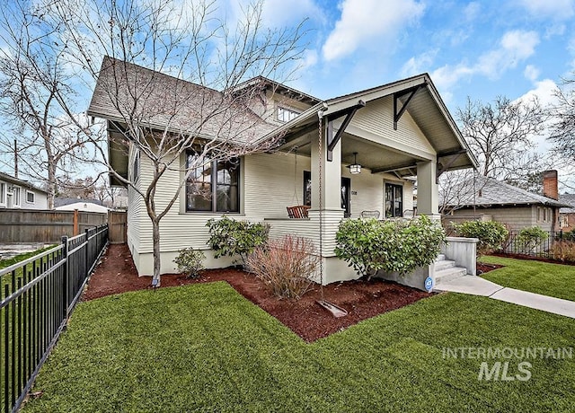 bungalow-style house featuring covered porch, a front lawn, and fence