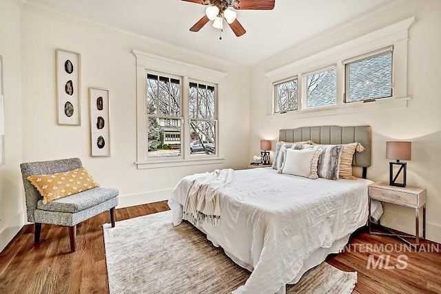 bedroom featuring ceiling fan, wood finished floors, baseboards, and ornamental molding