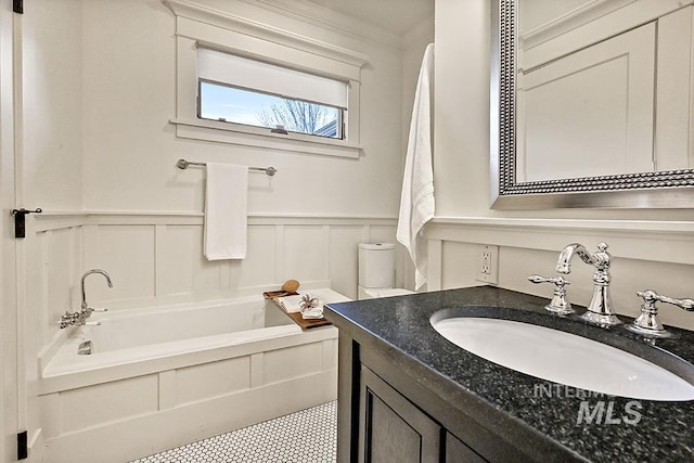 full bath with vanity, crown molding, a bathtub, and wainscoting