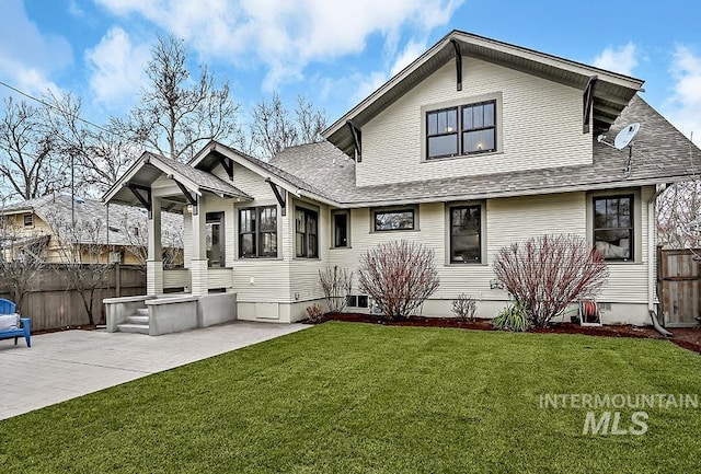 back of house with a lawn, a shingled roof, a patio, and fence