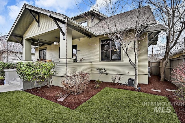 view of side of home with a yard, covered porch, and fence