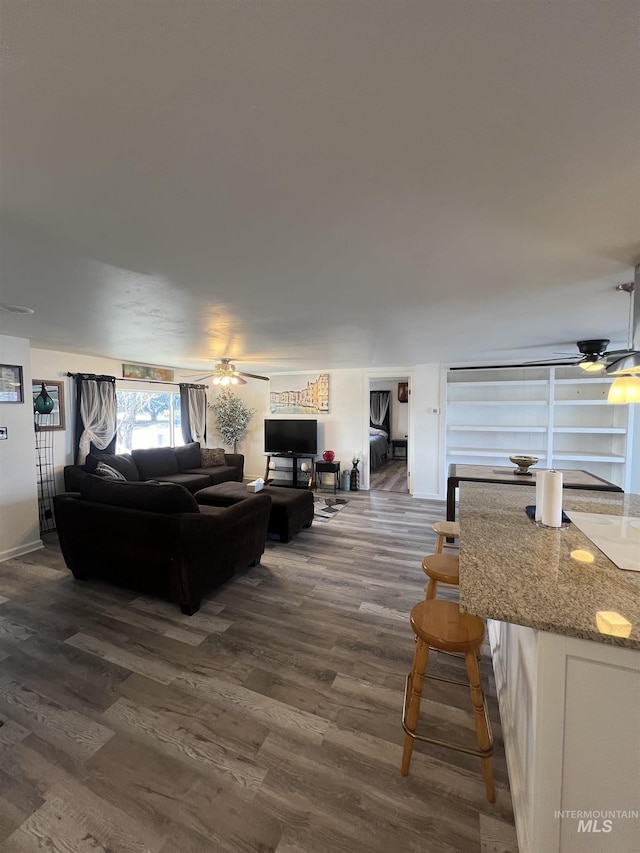 living area with a ceiling fan and dark wood finished floors