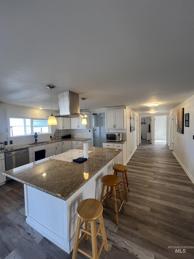 kitchen featuring appliances with stainless steel finishes, white cabinetry, a kitchen island, a sink, and island range hood