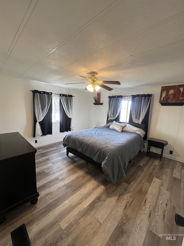 bedroom with a ceiling fan, multiple windows, and wood finished floors