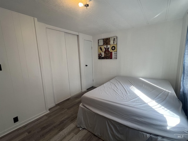 bedroom with dark wood-type flooring and a closet