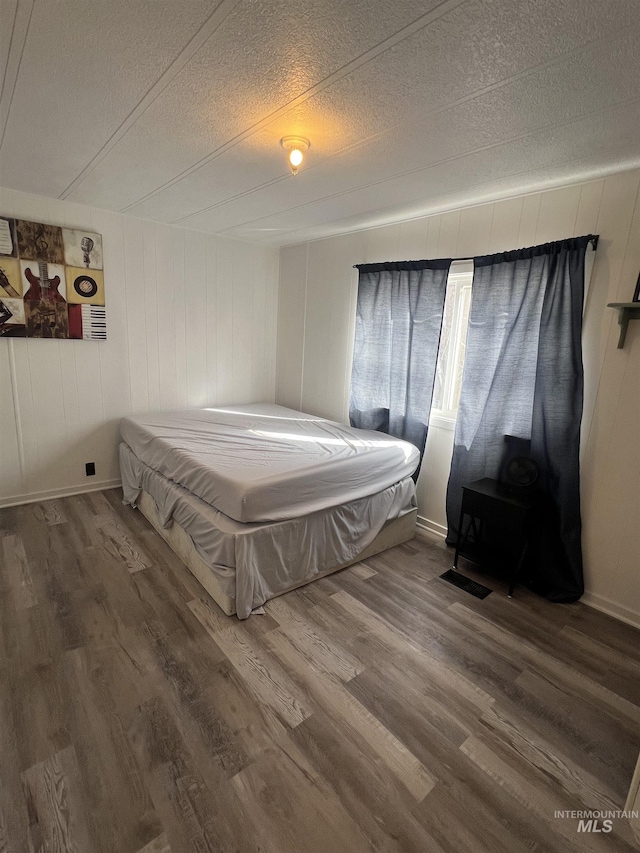 bedroom with a textured ceiling and wood finished floors