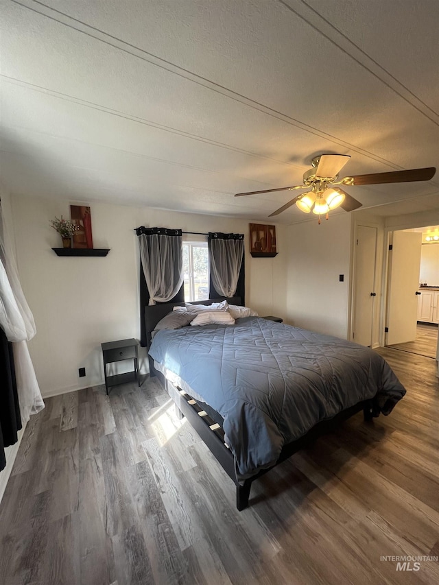 bedroom featuring a textured ceiling, wood finished floors, and a ceiling fan