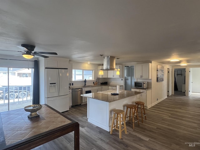 kitchen featuring island range hood, white cabinetry, appliances with stainless steel finishes, a center island, and dark wood-style floors