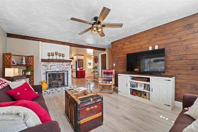 living area with a fireplace, wood walls, a textured ceiling, and wood finished floors