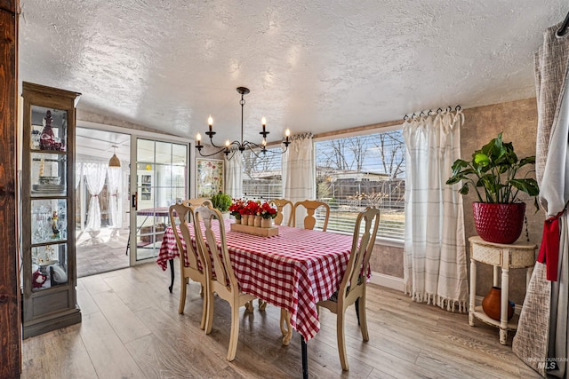 dining area with a textured ceiling, an inviting chandelier, and wood finished floors