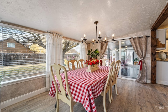 dining space with a chandelier, a textured ceiling, wood finished floors, and baseboards