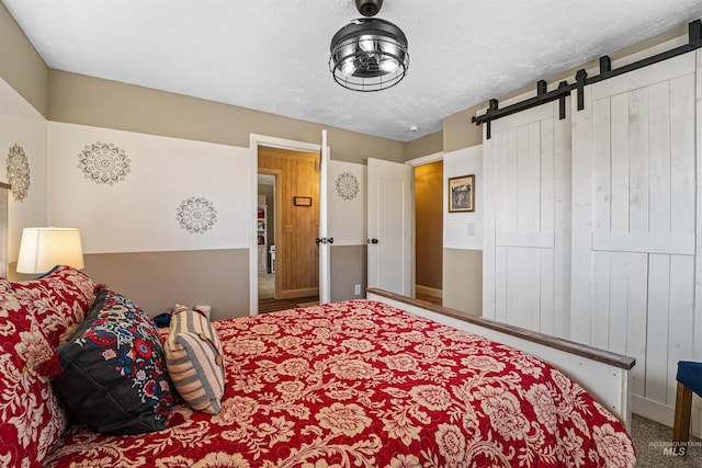 carpeted bedroom with a textured ceiling and a barn door