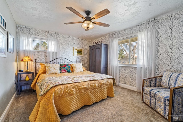 carpeted bedroom with a textured ceiling, baseboards, a ceiling fan, and wallpapered walls