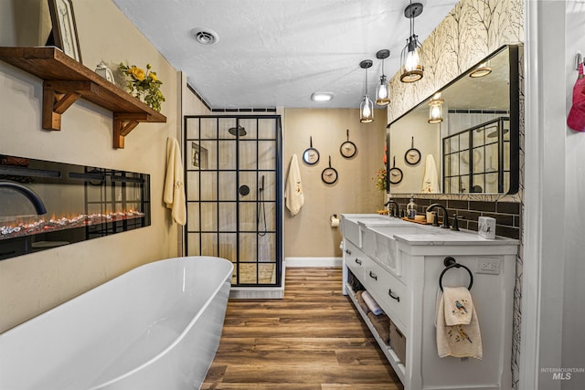 bathroom with visible vents, vanity, wood finished floors, a freestanding bath, and a textured ceiling