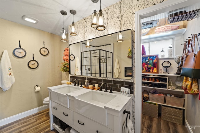 full bathroom with toilet, a sink, wood finished floors, baseboards, and double vanity