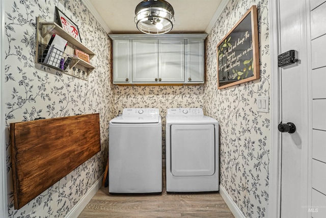 washroom with cabinet space, washer and clothes dryer, and wallpapered walls