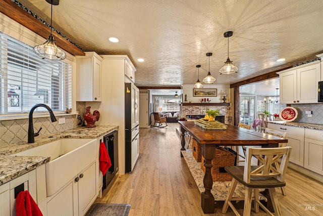 kitchen featuring light wood-type flooring, light stone counters, backsplash, and a sink