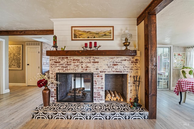 living room with a brick fireplace, visible vents, a textured ceiling, and wood finished floors