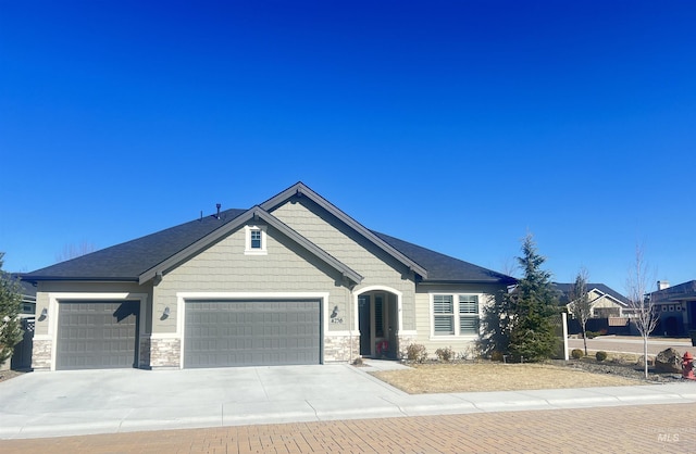 view of front of house featuring an attached garage, stone siding, and driveway