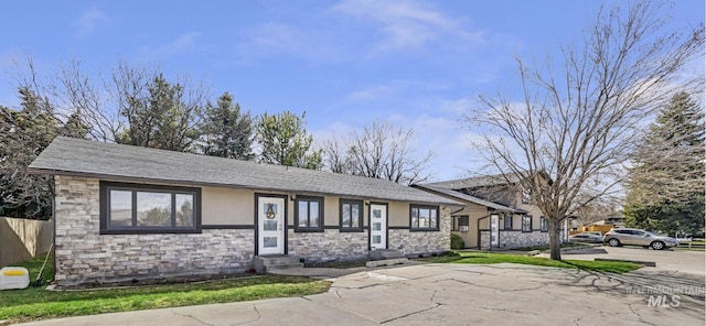 ranch-style house with fence, entry steps, stucco siding, and stone siding