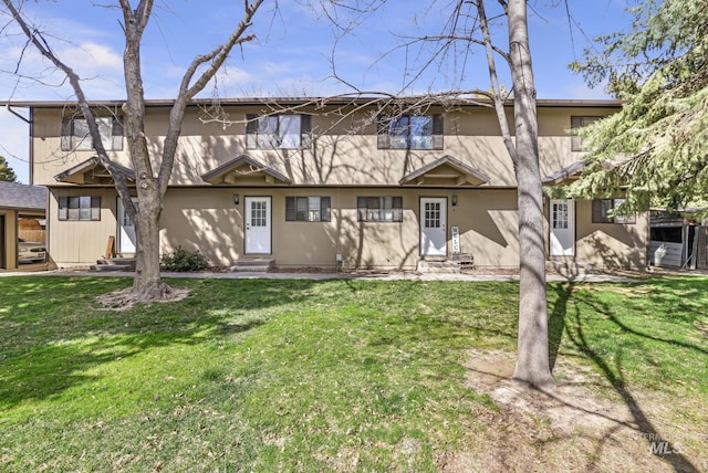 back of house featuring a yard, stucco siding, and entry steps