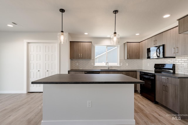 kitchen featuring pendant lighting, a center island, black appliances, and light wood-type flooring