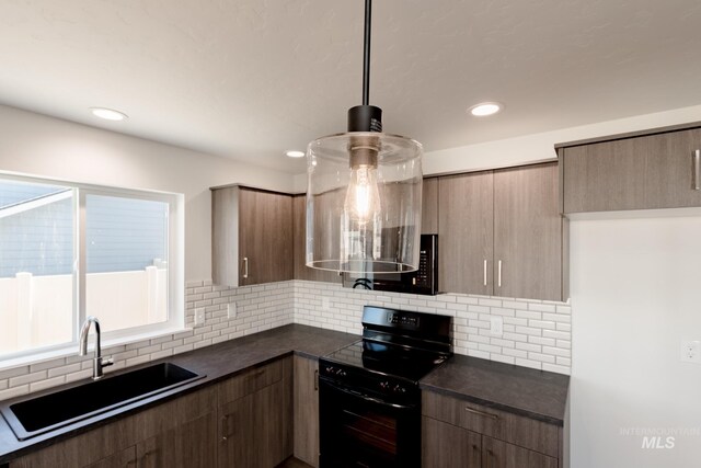 kitchen featuring tasteful backsplash, black range with electric stovetop, sink, and hanging light fixtures