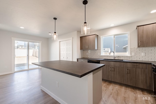 kitchen featuring decorative backsplash, sink, decorative light fixtures, light hardwood / wood-style floors, and a kitchen island